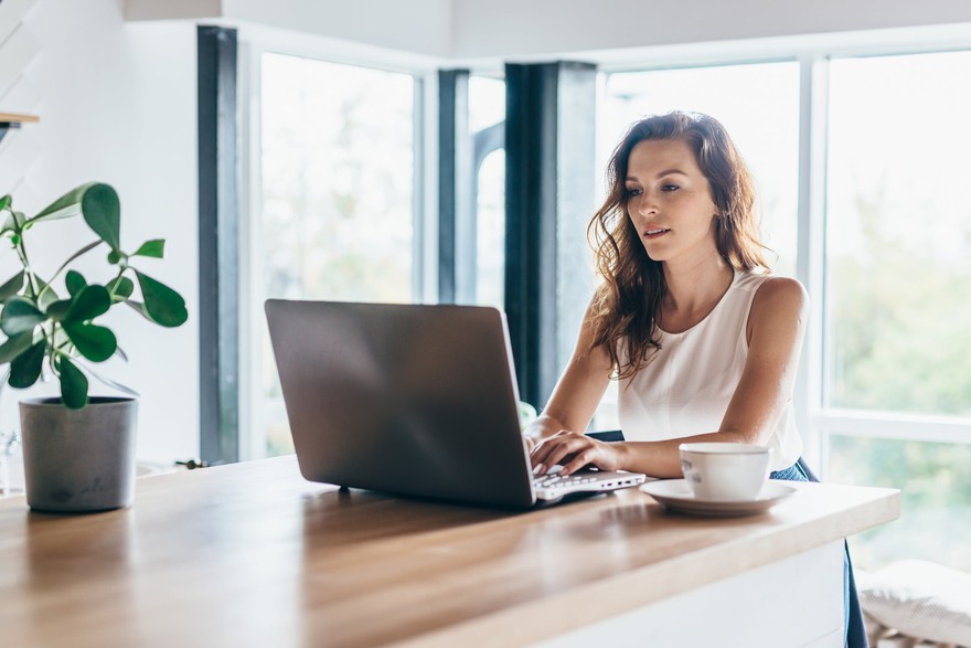 A woman using a laptop while sitting at a counter.