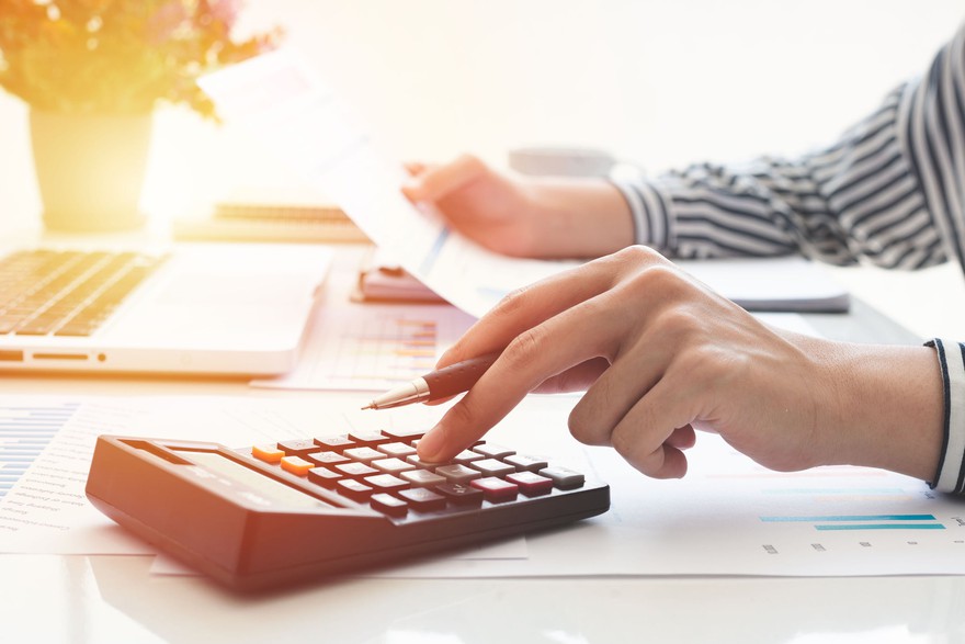 Person using calculator and looking at statement. Person using calculator and looking at statement.