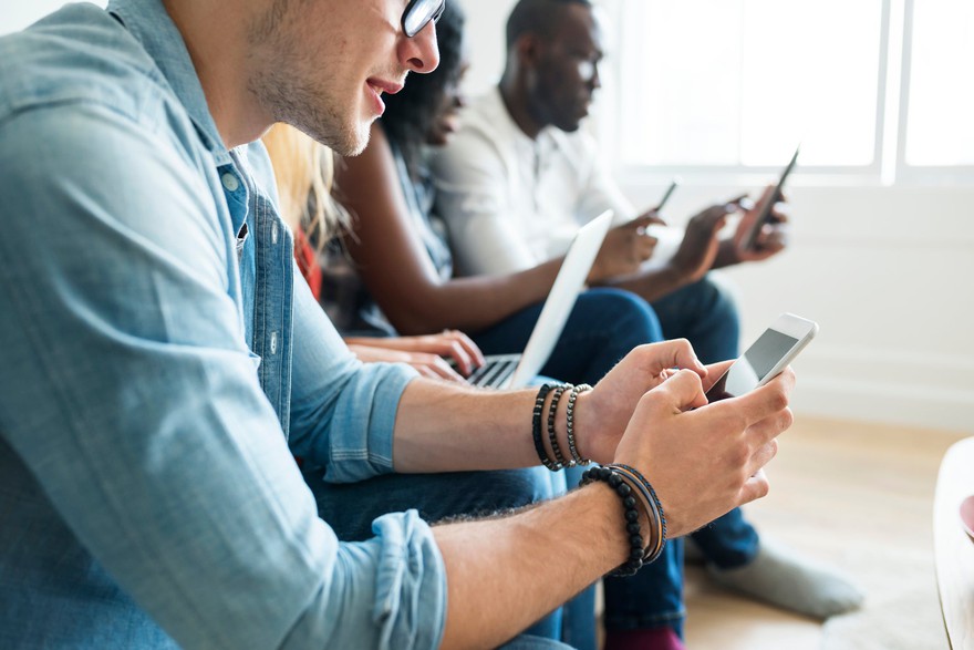 People seated using different technological devices. People seated using different technological devices.