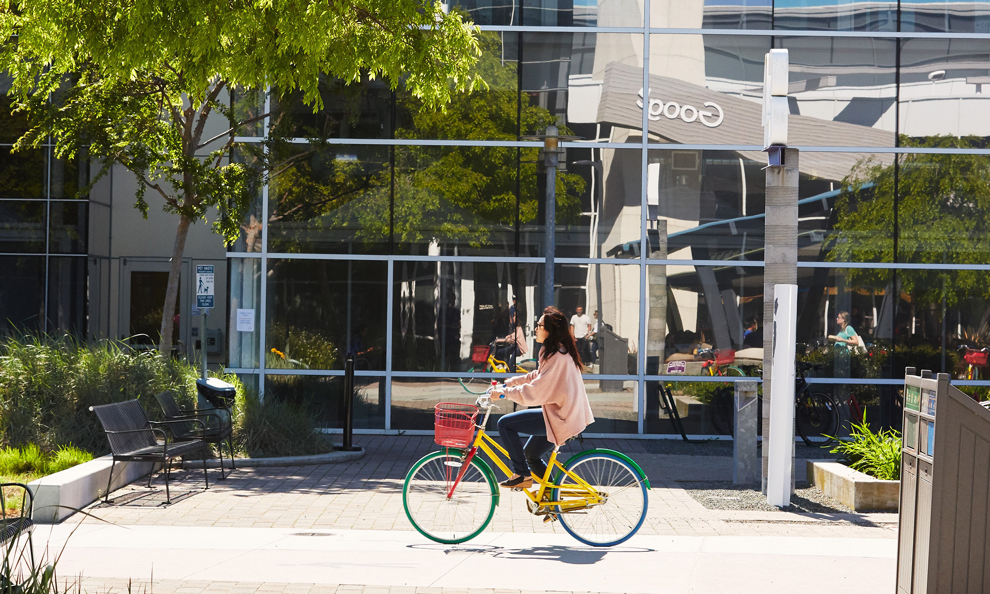 person biking on google campus with google logo reflection in background_alphabet_google