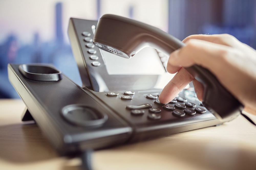 Person using a telephone on a desk. Person using a telephone on a desk.