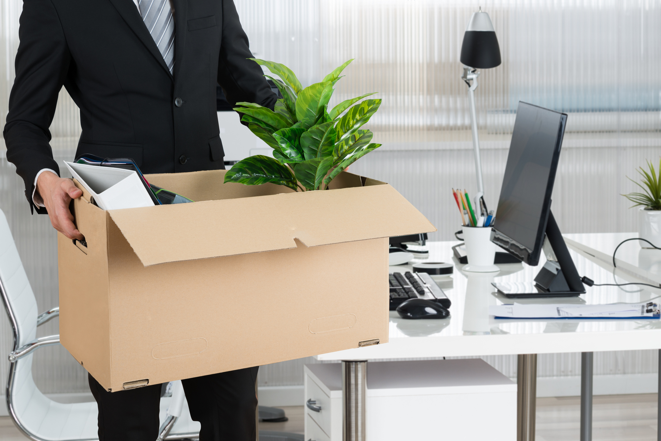 Quit A person leaves an office with a box of belongings.
