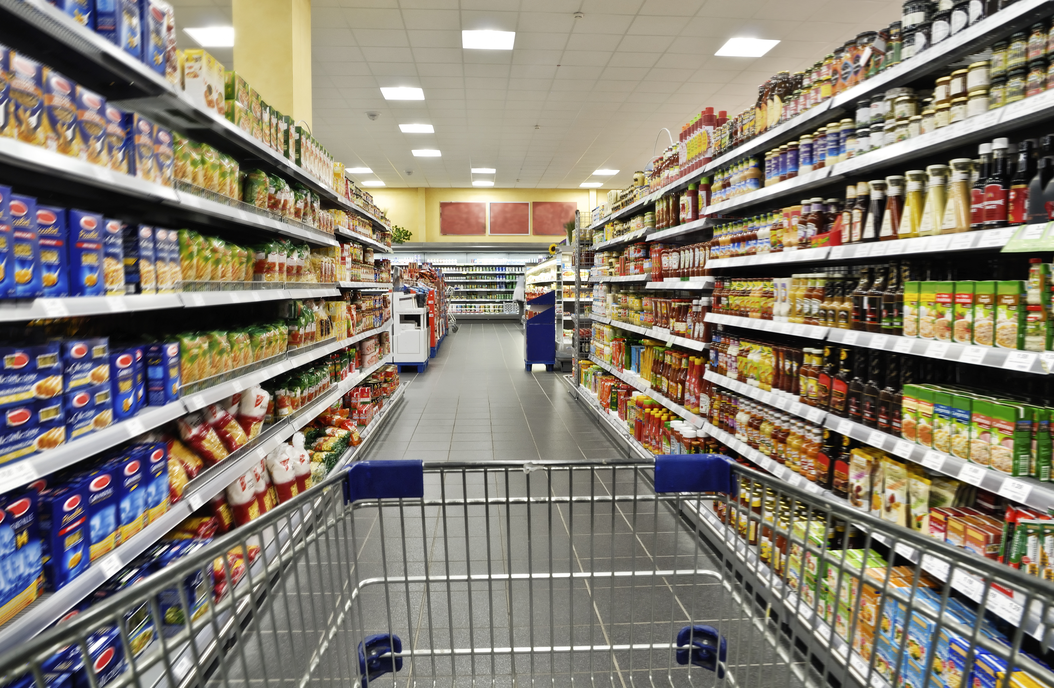 Cart in grocery store aisle A shopping cart being pushed down a grocery store aisle.