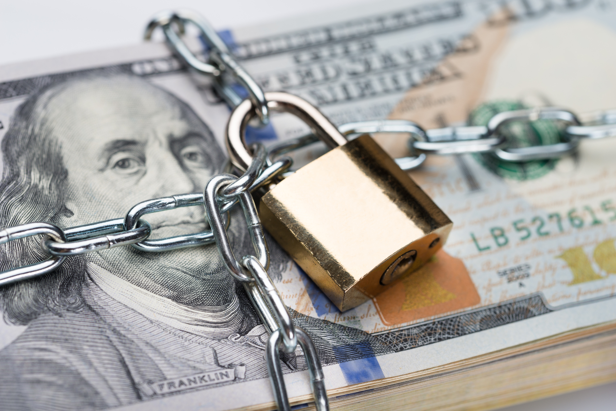 A stack of hundred dollar bills in a chain and padlock.