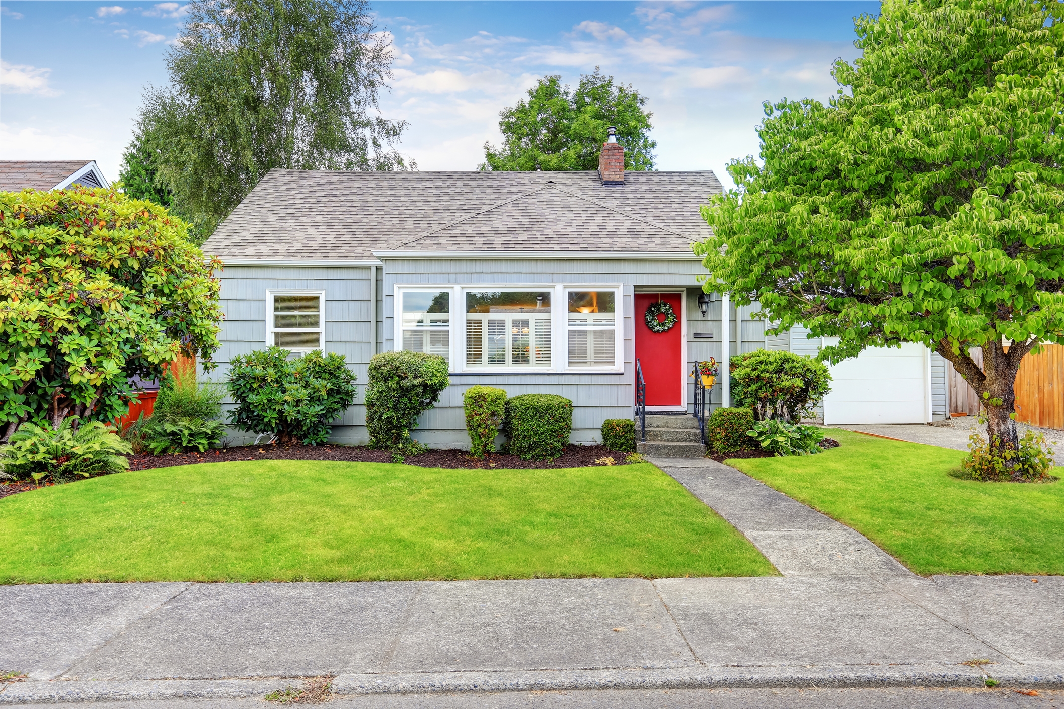 A small house with a front yard in a suburban neighborhood. A small house with a front yard in a suburban neighborhood.
