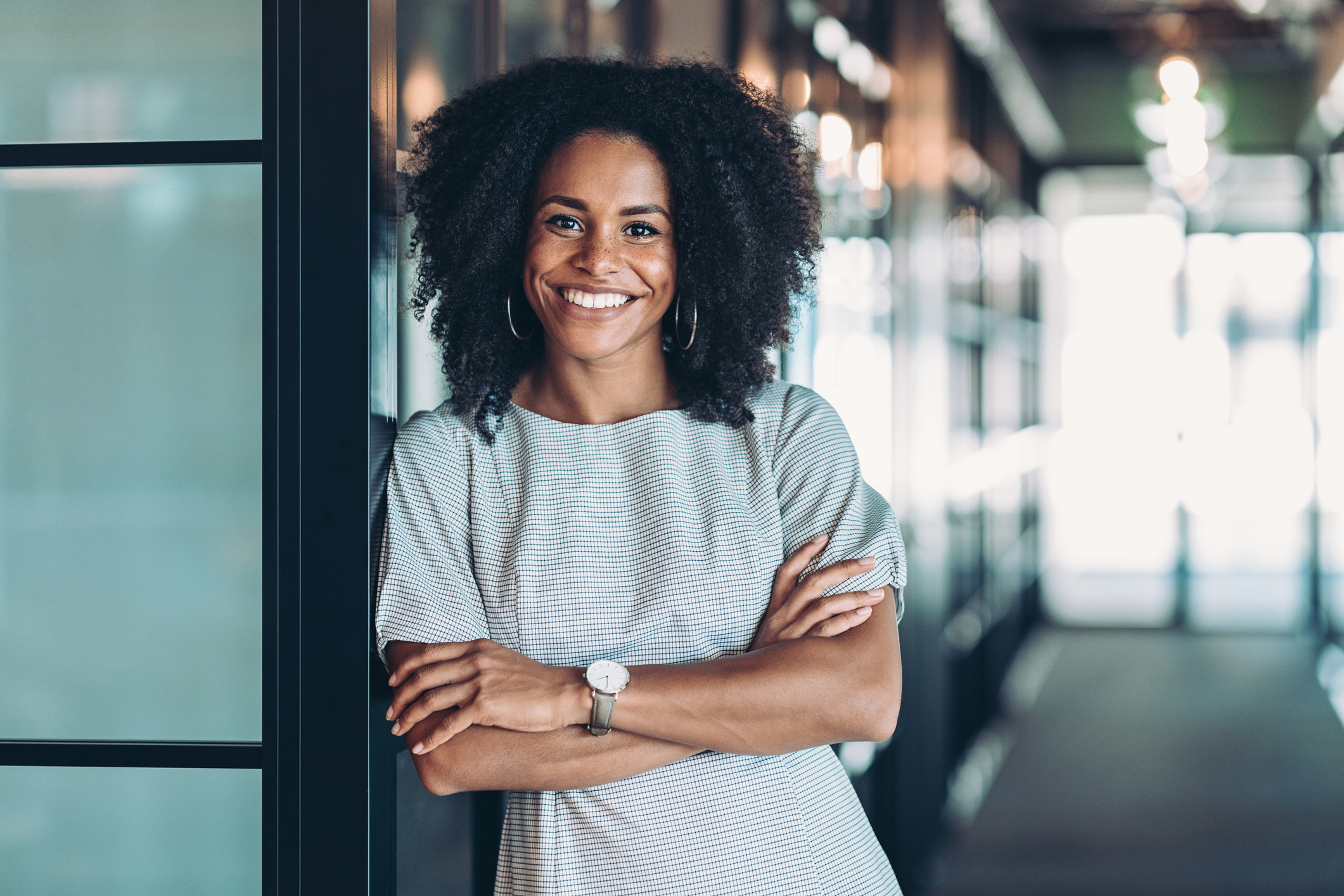 smiling-person Person smiles broadly while leaning against wall in office.