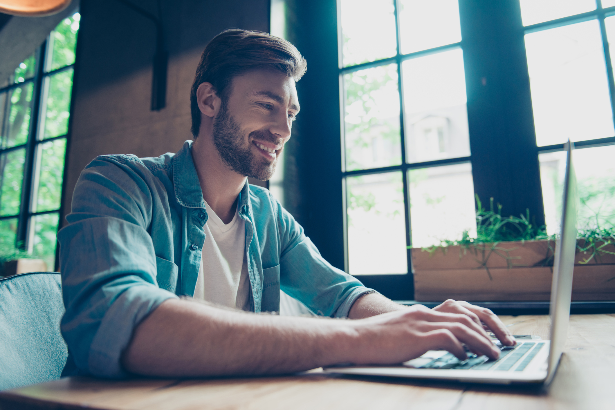 Smiling man typing on laptop Smiling person typing on laptop.