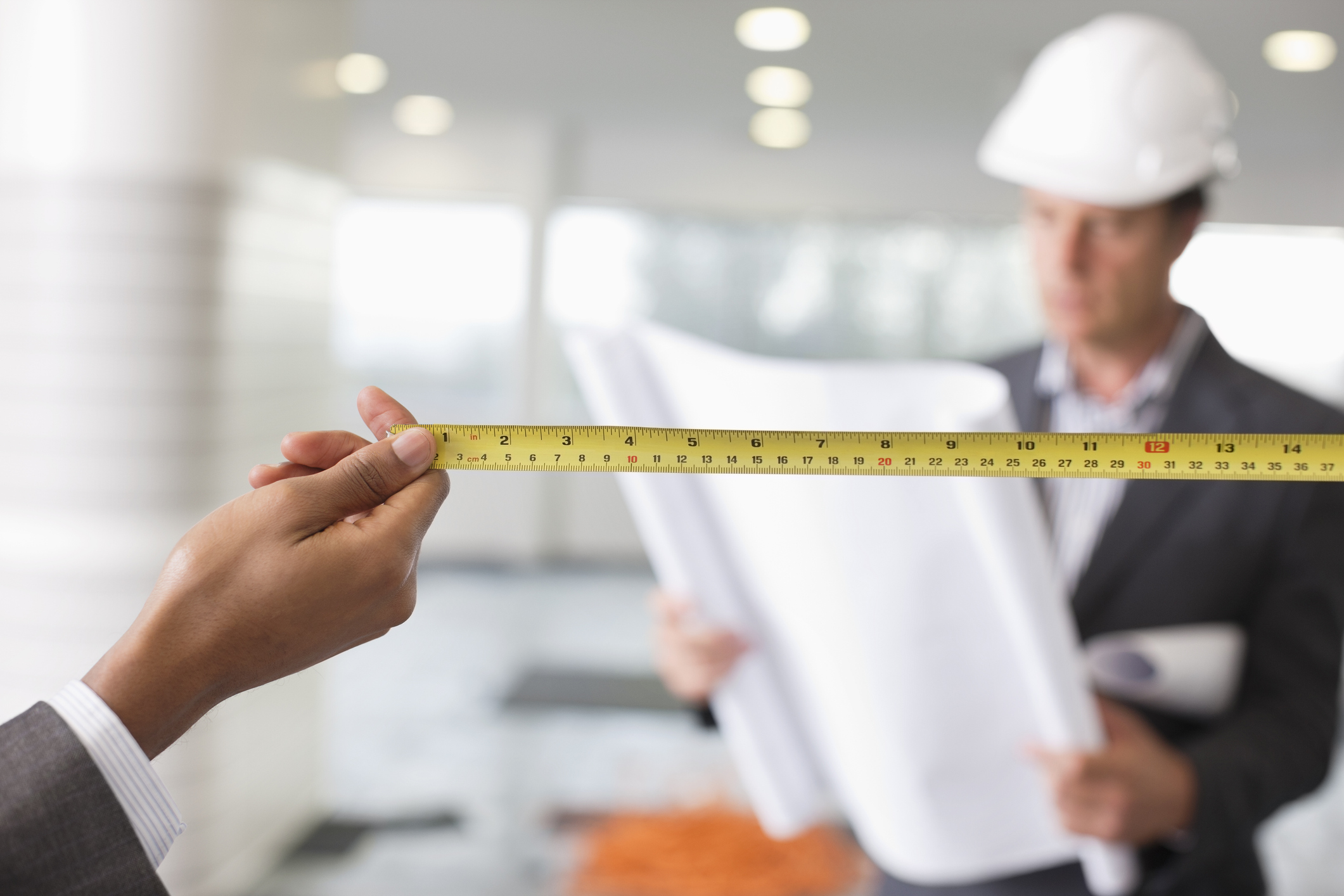 Construction workers inside a building with measuring tape and blueprint working on a store buildout