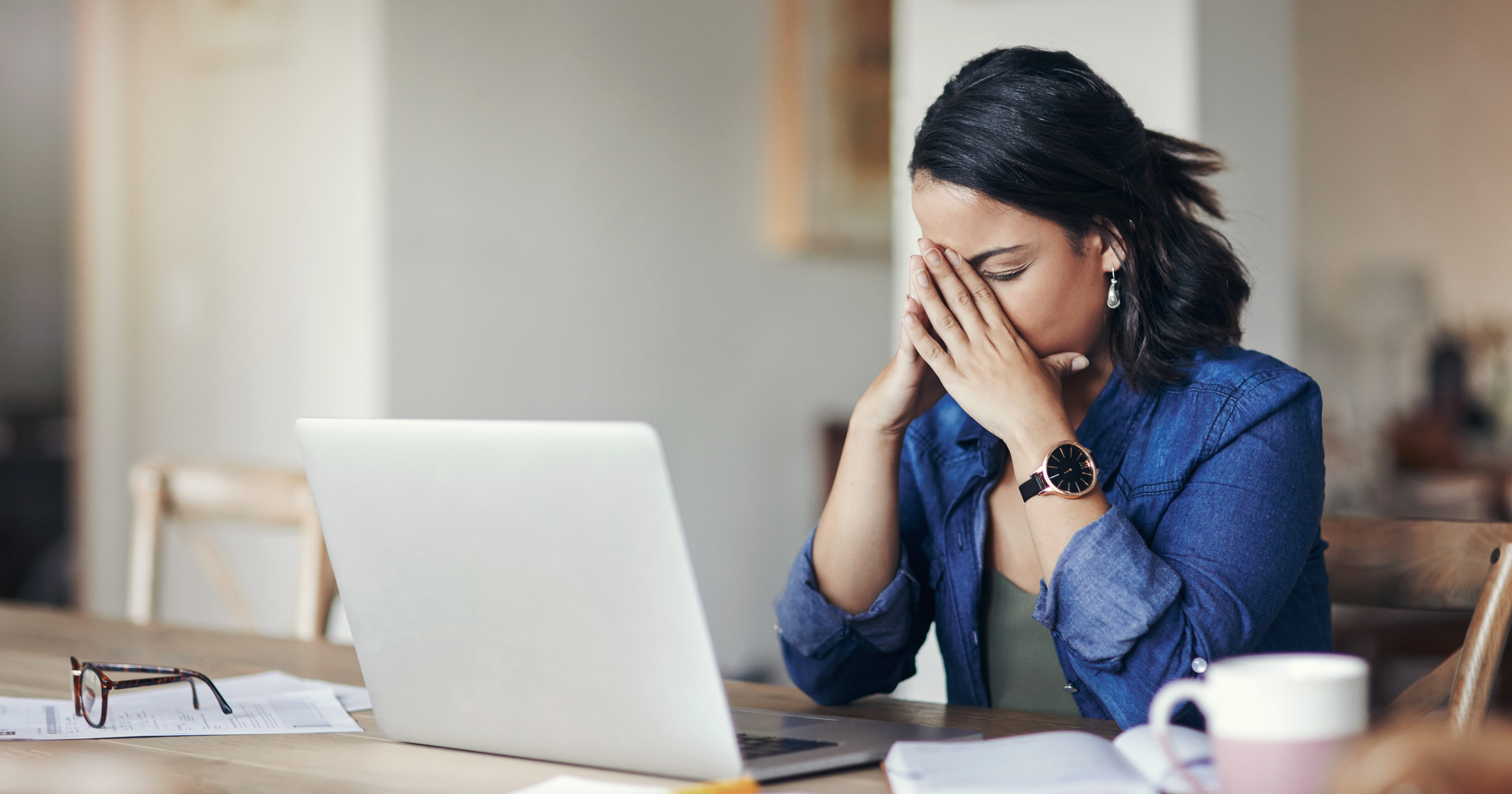 Person looking stressed while using a laptop.