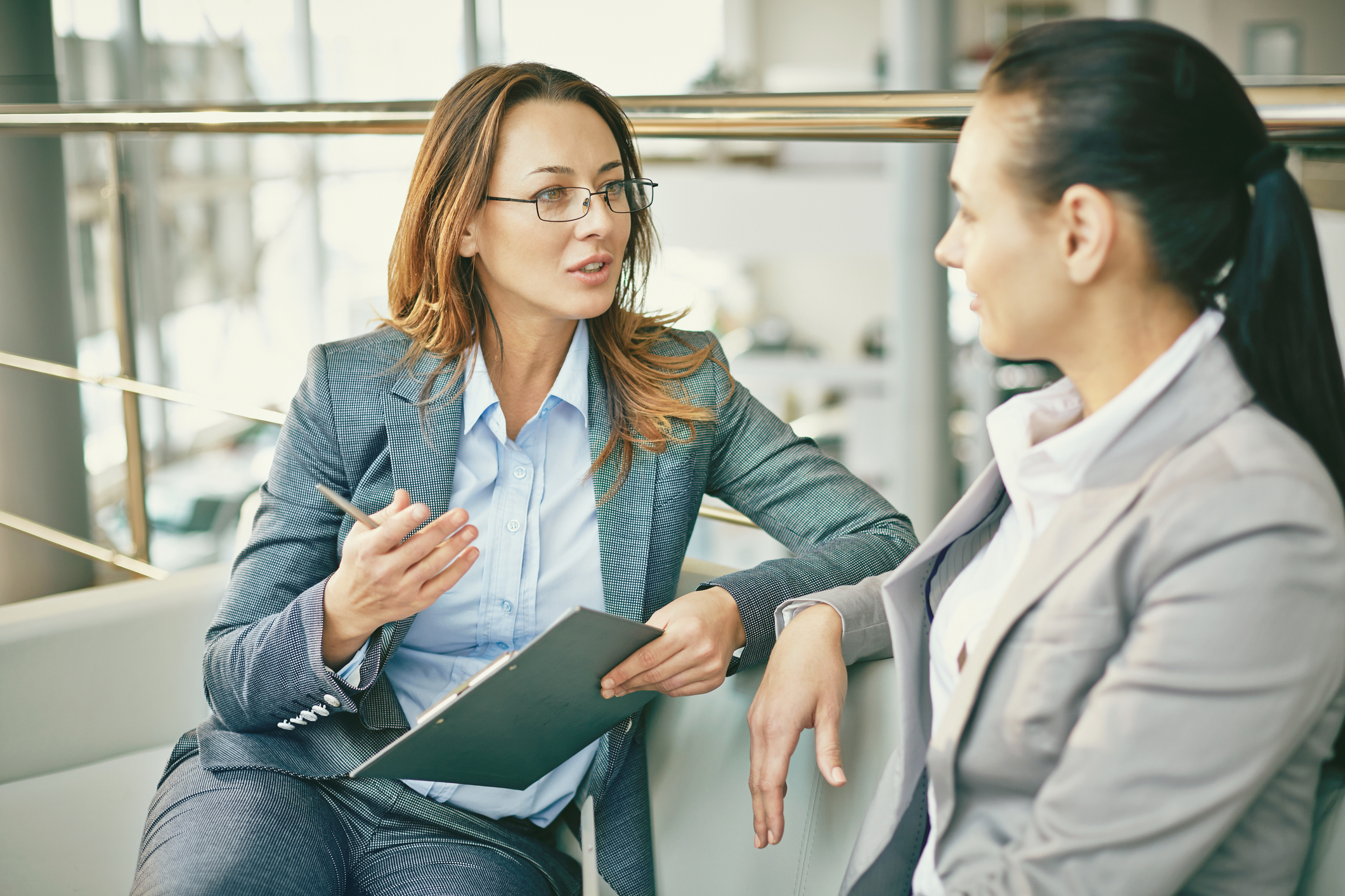 Two women in business suits talking. Two women in business suits talking.