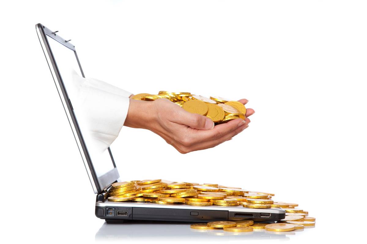what_is_accounting_profit Laptop with gold coins to show accounting profit from software development.