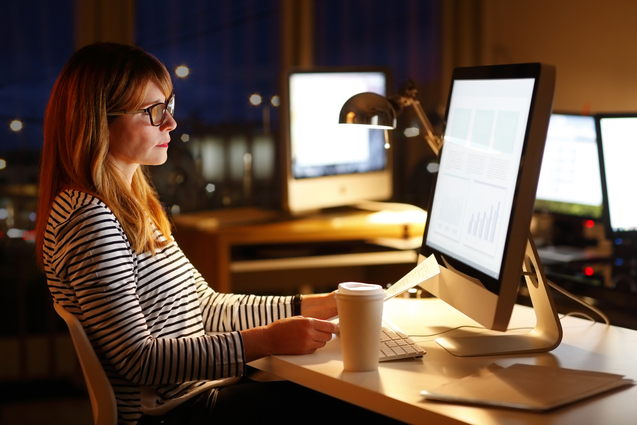 woman sitting in front of computer in office late at night -- working job stress businesswoman