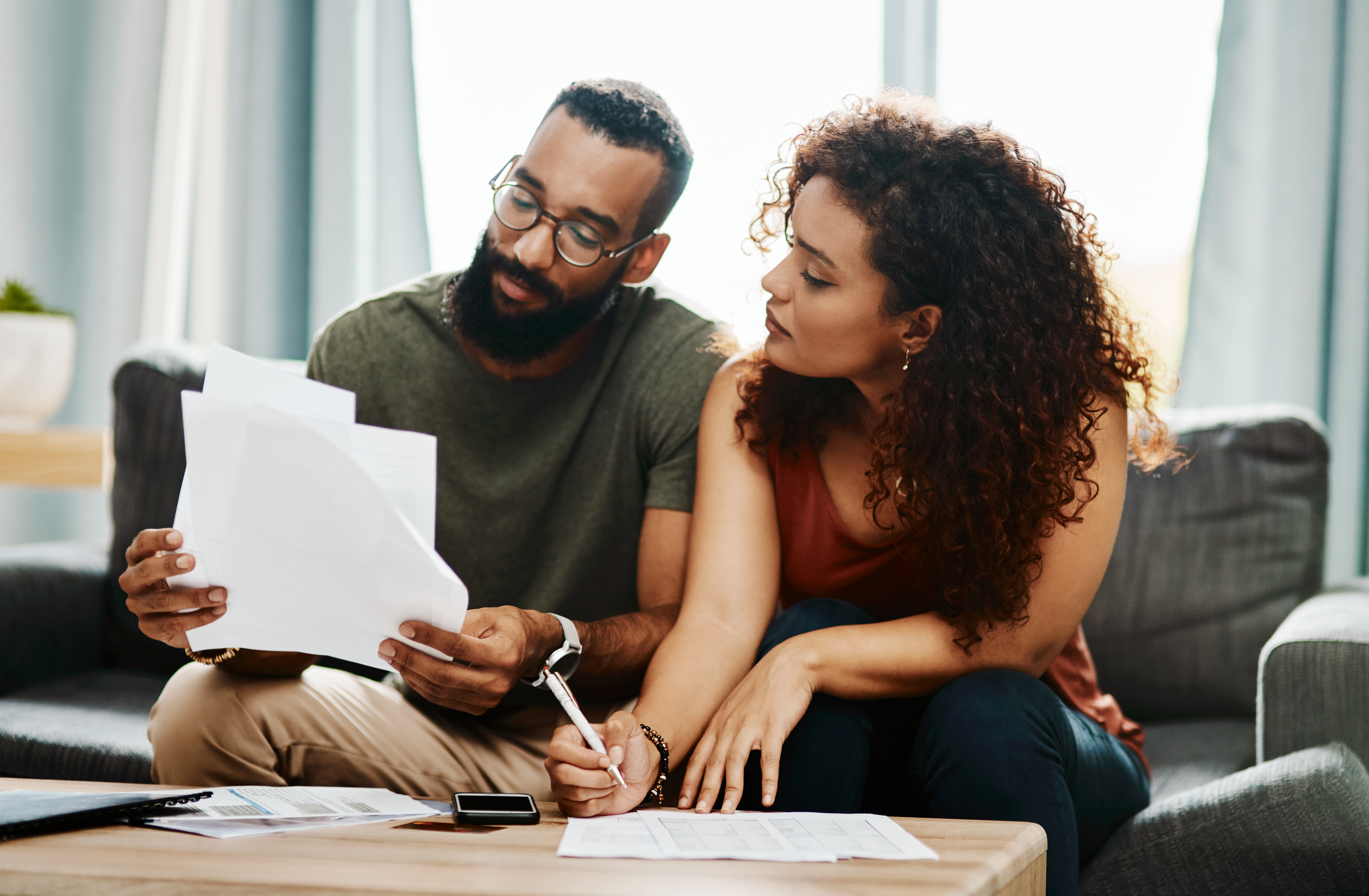 Two individuals review paperwork at home. Two individuals review paperwork at home.