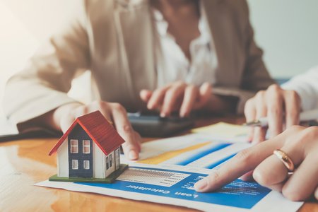 pointing a a contract next to a model house