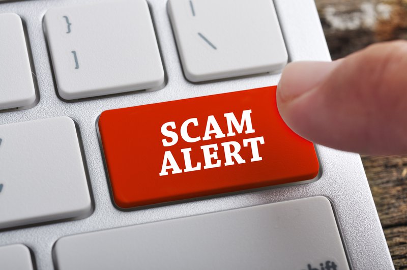 Finger pushing scam alert button