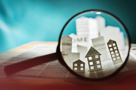 magnifying glass showing newspaper popups of buildings