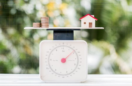 Coins and a house model on a scale