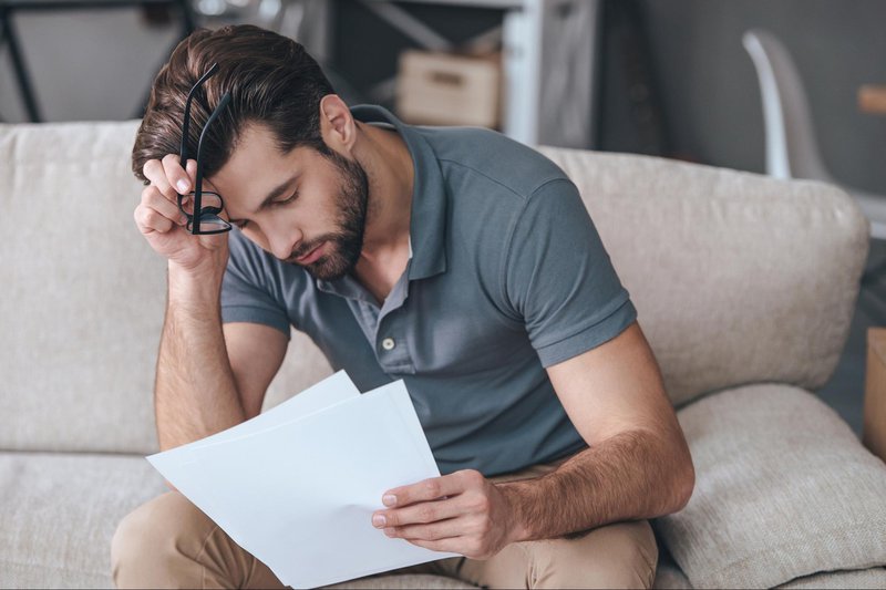 Man looking at documents with glasses off