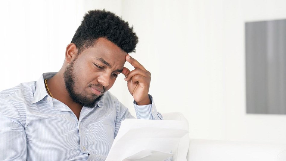 Man holding head and looking at documents