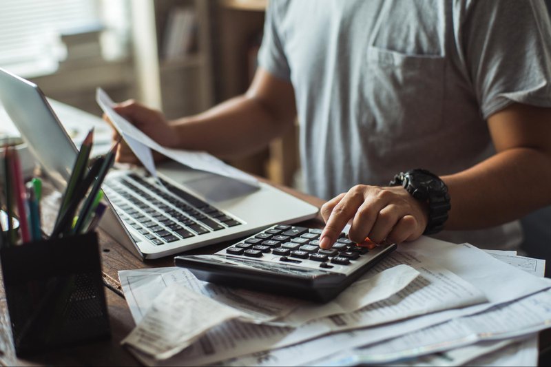 Man in t-shirt in front of a computer and calculator