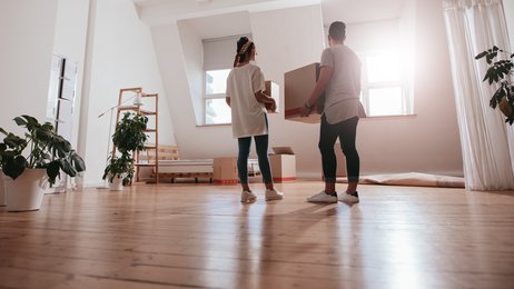 Young man and woman holding boxes and moving in new house.