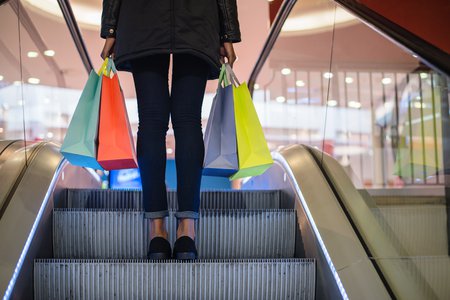 Person on escalator carrying shopping bags