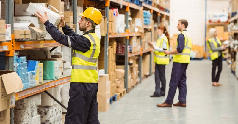 A group of warehouse workers pick items off the shelves to pack for fulfillment.